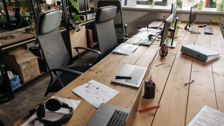 Shared office desk with laptops, notebooks and stationery