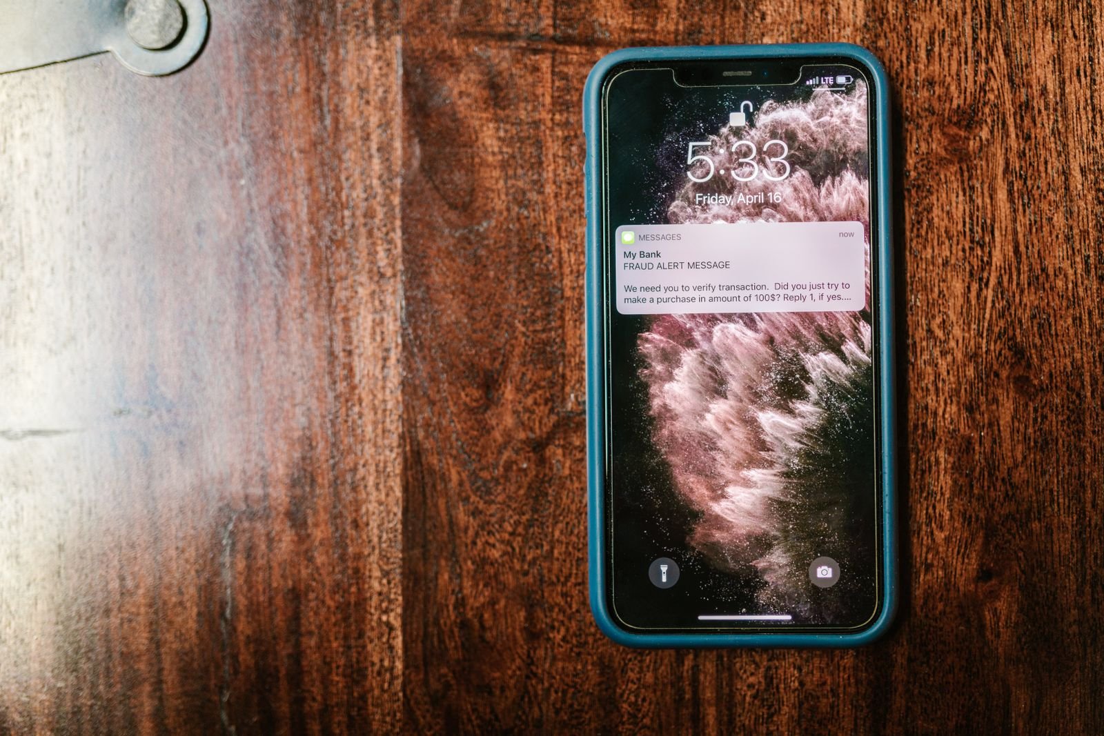 A phone resting on a desk beside a notebook