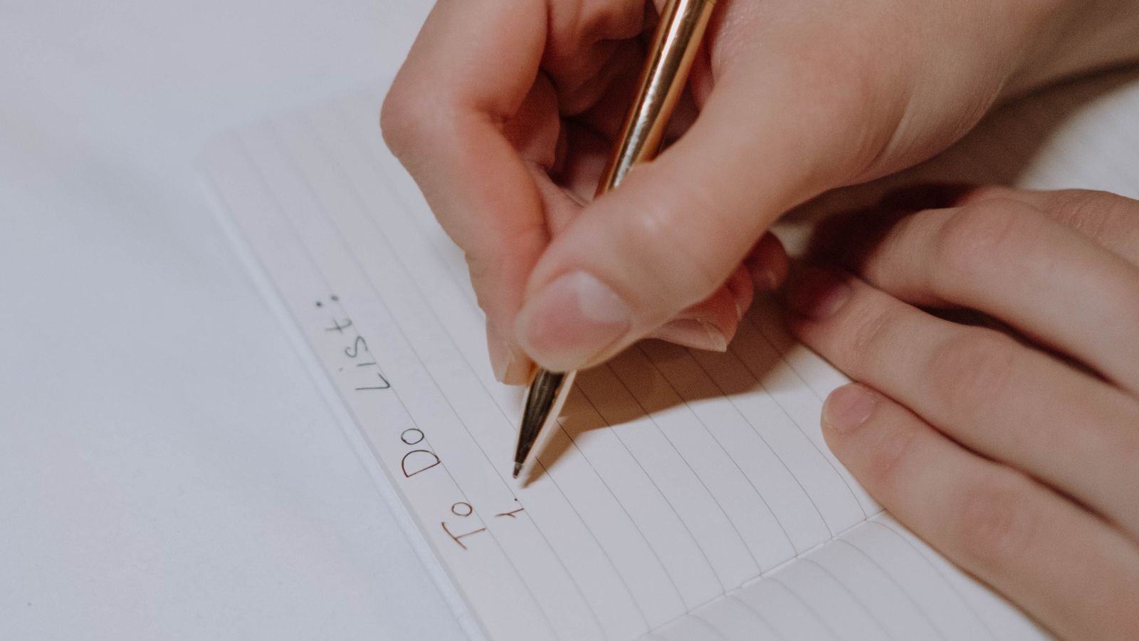 Notebook with a to-do list beside a laptop