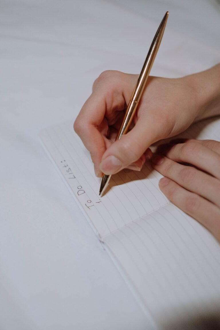 A handwritten to-do list on a notepad beside a phone