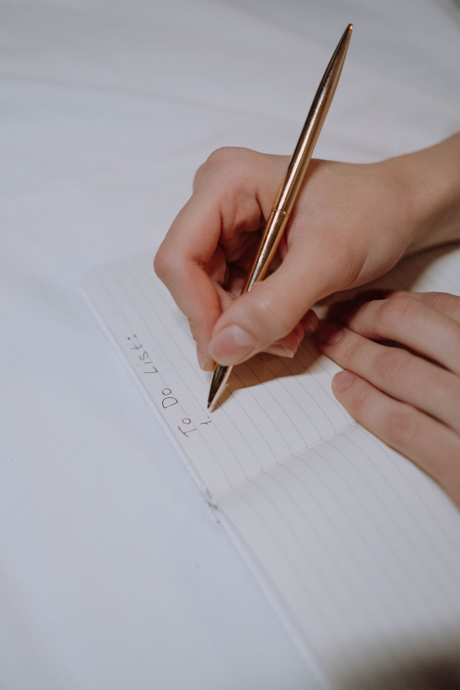 A handwritten to-do list on a notepad beside a phone