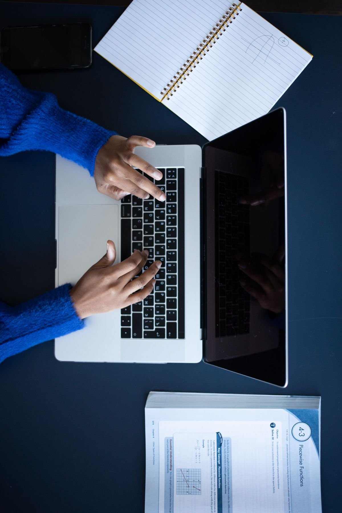 Person typing on a laptop while working with documents