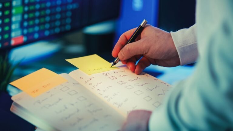 Person writing a task checklist in a planner on a desk